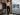 Man styling black jeans with a shirt beside a rain-streaked window | 