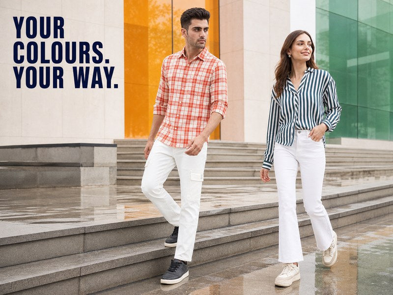 Man and woman in Spykar white jeans with orange and green shirts on rain-washed urban steps | 